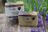 Two bars of Twilight Soap Company Chocolate Lavender soap on a wooden surface with a dark background.