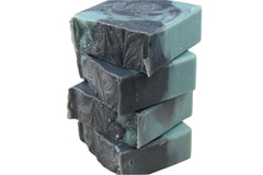 Stack of green soap bars on a wooden surface with a dark background