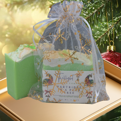 Green soap bar next to a decorative gift bag on a wooden surface with a dark background