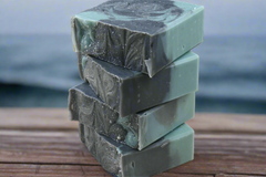 Stack of green soap bars on a wooden surface with a dark background