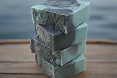 Stack of green soap bars on a wooden surface with a dark background