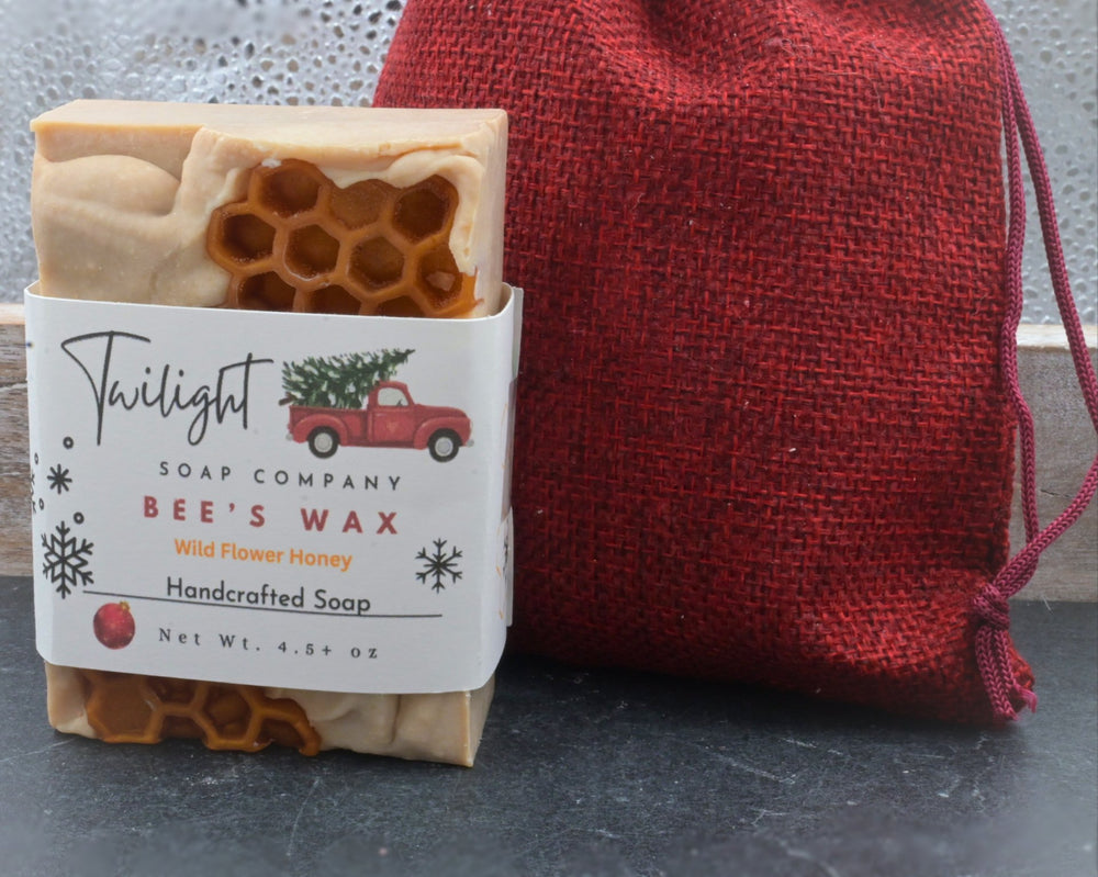 Bar of soap with a label from Twilight Soap Company next to a red drawstring bag on a dark surface.