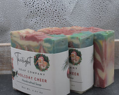 Three bars of soap with colorful swirls and 'Twilight Soap Company Holiday Cheer' labels on a textured surface.